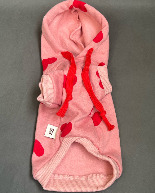 UNA SUDADERA CON CAPUCHA EN COLOR ROSA Y ESTAMPADO DE CORAZONES ROJO. MANGA LARGA, SE METE TIPO JERSEY, SIN CIERRES NI BOTONES. ES CALIENTITA PORQUE POR DENTRO ES UNA FELPITA DE PIEL DE DURAZNO.IDEAL PARA PERRO Y GATO DE RAZAS PEQUEÑAS A MEDIANAS.